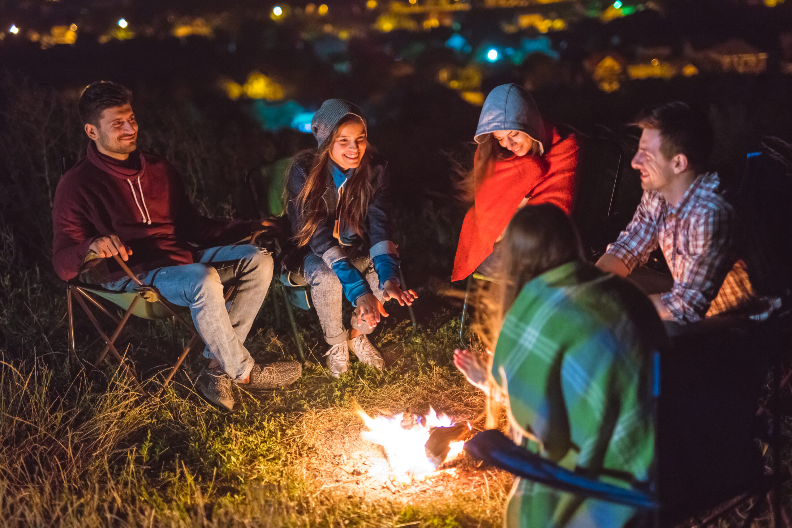 The happy people sit near the bonfire. evening night time
